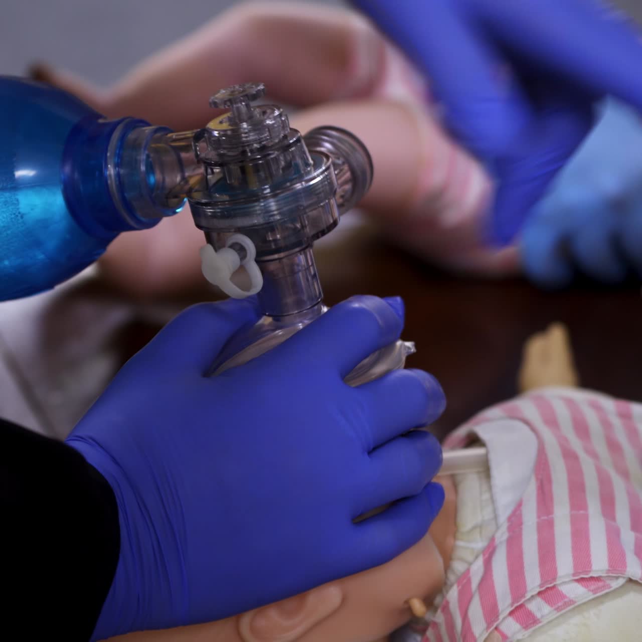 Breathing session on a doll. Hands in medical gloves doing chest compression on a baby mannequin. Training cpr procedure in rescue center. Close-up