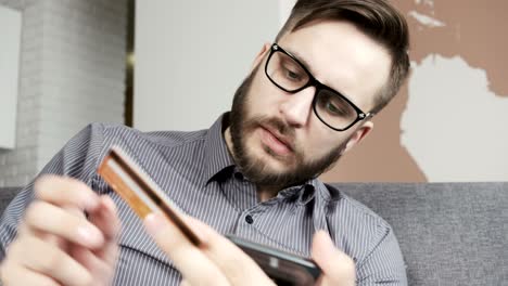 hombre pagando en línea con tarjeta bancaria en su teléfono inteligente