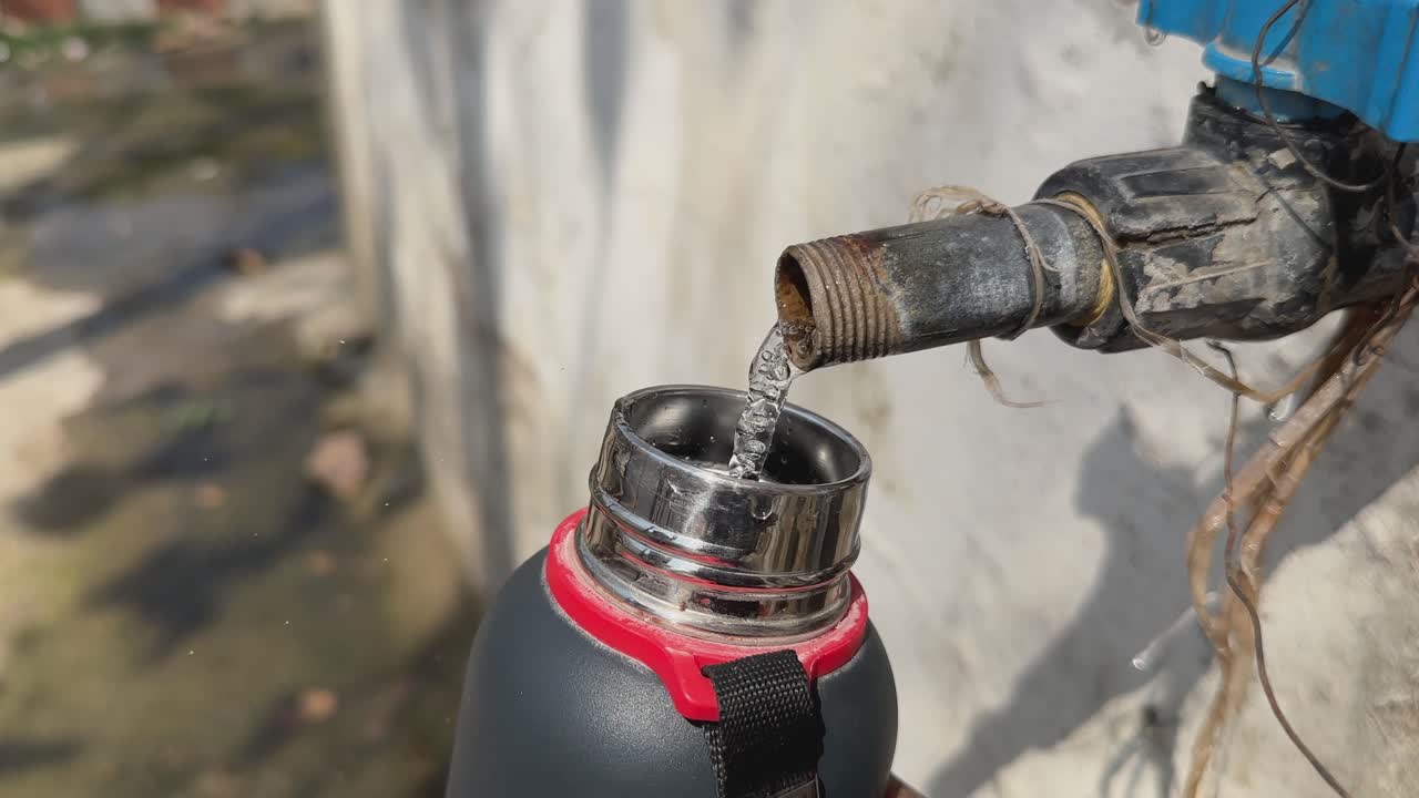 closeup of filling a water bottle from the open tap