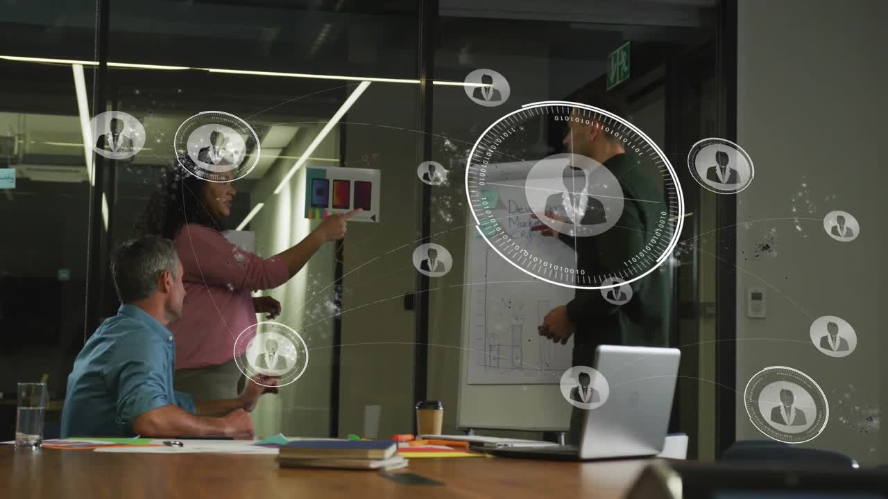 Standing man pressing remote and pointing swatches, team reviewing design with HUD overlays growing