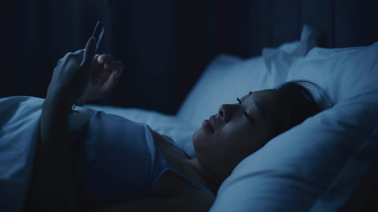 밤에 침대에서 드폰을 사용하는 여자