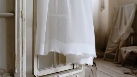 white sheer curtain blowing in a rustic window