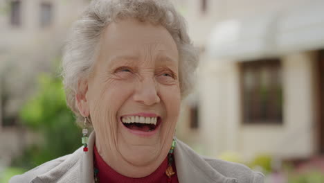 portrait of elderly caucasian woman laughing cheerful looking at camera enjoying happy retired lifestyle in sunny outdoors slow motion