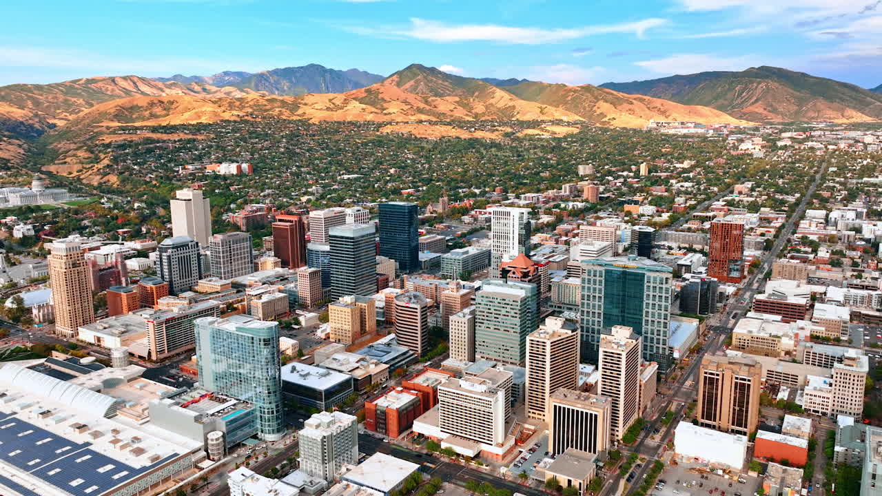 Salt Lake City, USA, 14 August 2025: High-rise downtown of the city against green low-rise residential area. Beautiful bare mountains at backdrop. Salt Lake City, Utah, USA. Aerial view