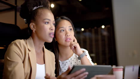 young african american woman and biracial woman collaborate in a business office