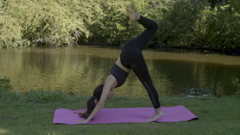 Pretty-Young-woman-doing-warrior-poses-near-pond