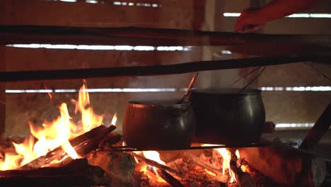 una olla de cocción se coloca por encima de una llama cruda mientras alguien agita la comida dentro