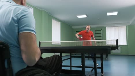 a man in a wheelchair plays ping pong. people with disabilities play table tennis. rehabilitation of the disabled. paralympic sport.