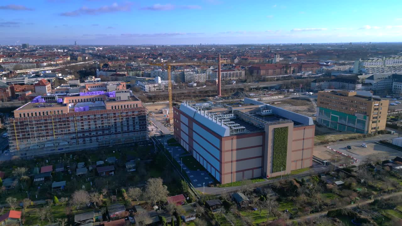 Moderno edificio di data center caratterizzato da una facciata a parete verde, che rappresenta l'infrastruttura tecnologica e il calcolo sostenibile in un paesaggio urbano. Fluida vista aerea discendente da drone