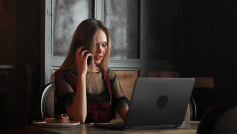 happy businesswoman sitting at the table and talking on the phone in cafe. looking away