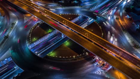 4k time lapse vista aérea de la intersección de la rotonda de la carretera en la ciudad por la noche con movimiento ligero de vehículos.