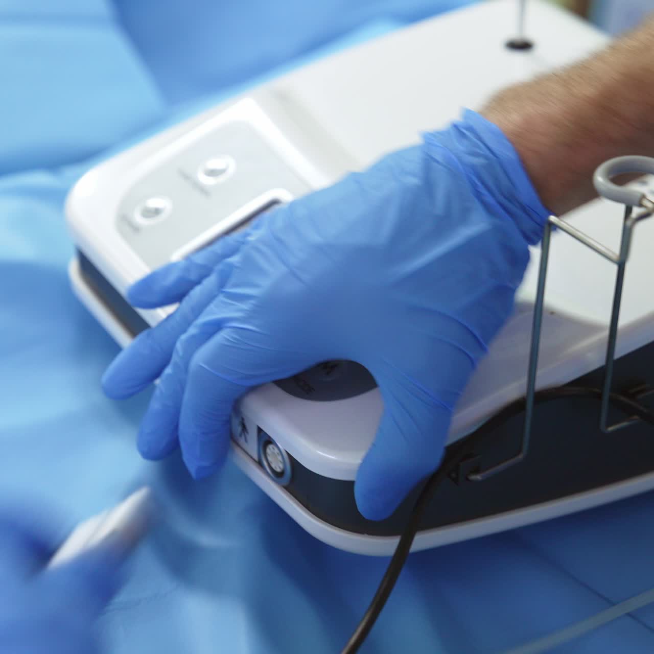 Assistant's hands touching the apparatus for otolaringology surgery. Special equipment being unplugged and wires disconnected. Close up