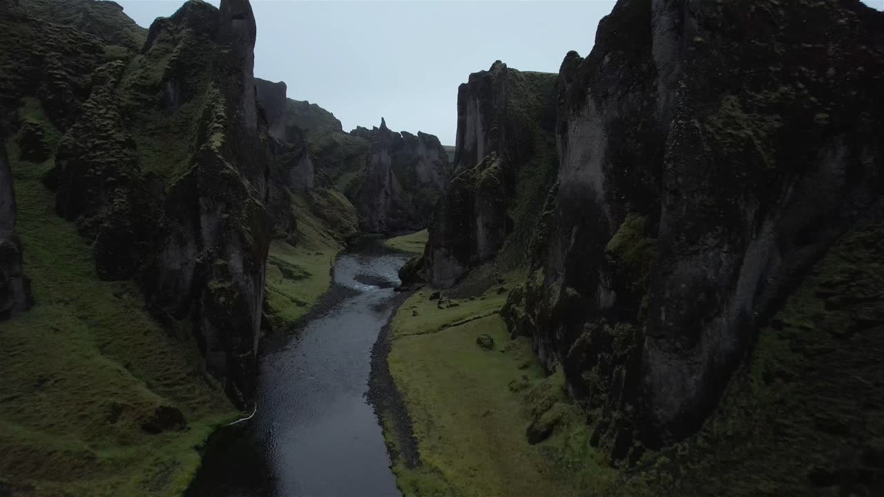 disparo de drones volando bajo a través del cañón de roca fjaðrárgljúfur con el río debajo en islandia en 4k