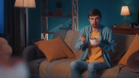 man eating ice cream on couch at night