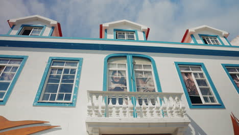 wide shot of old white building with big turquoise painted windows in the azores islands, portugal