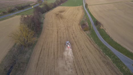 Small-blue-tractor-preparing-a-brown-dusty-field-for-the-spring-time-in-Germany