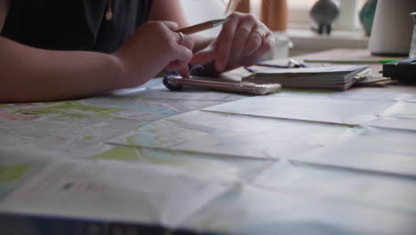 close-up of hands planning a route on a city map, surrounded by travel essentials