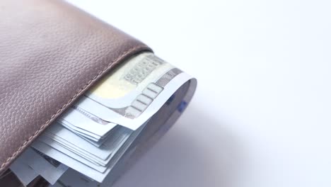 close-up of a brown leather wallet filled with us dollar bills