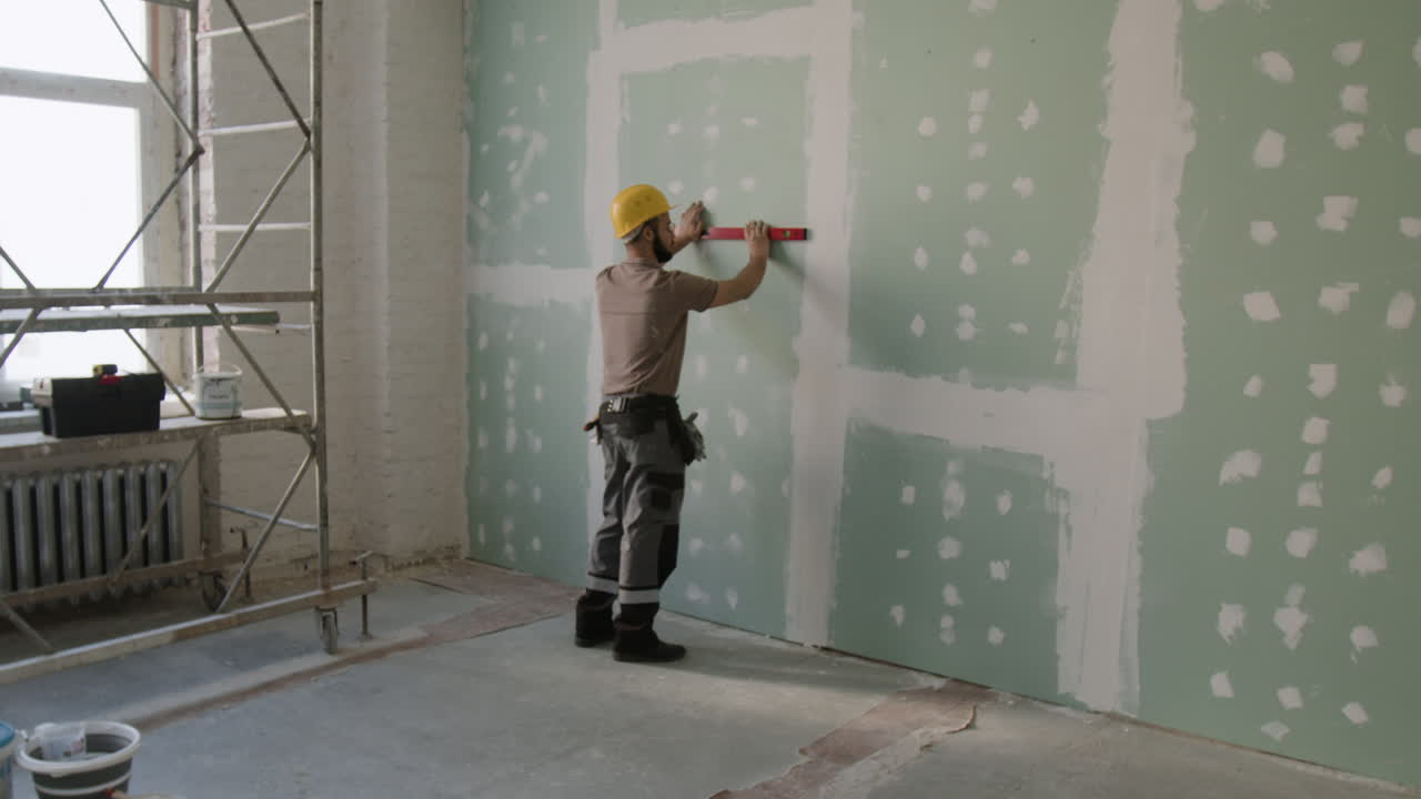 Construction worker leveling drywall in a renovated room
