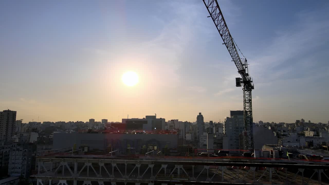 vista aérea de la grúa de construcción oscilante en el sitio contra el cielo vibrante de la puesta de sol