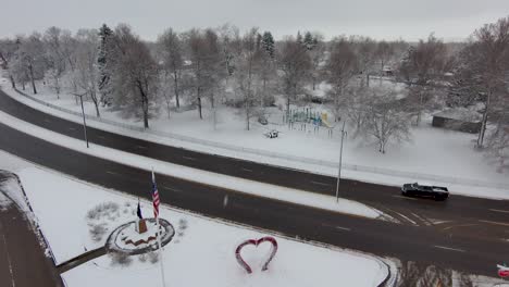 a drone flies backward through a heart shaped sculpture to reveal loveland colorado covered in snow