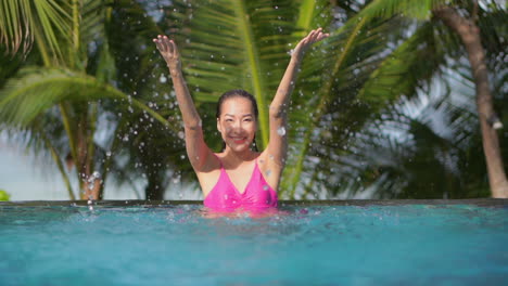 Young-asian-woman-plays-with-water-in-pool