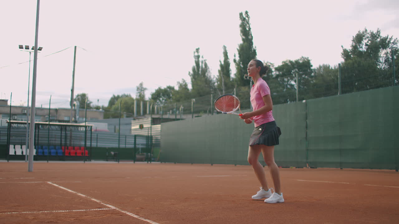 Athletic Young Woman Tennis Player. Portrait of handsome woman with tennis racket in the tennis uniform walking outdoor.