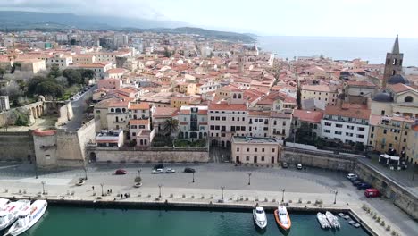 Toma-Aérea-Sobre-El-Casco-Antiguo-De-Alghero,-Cerdeña,-Con-Vistas-Al-Paisaje-Urbano-En-Un-Hermoso-Día-Claro