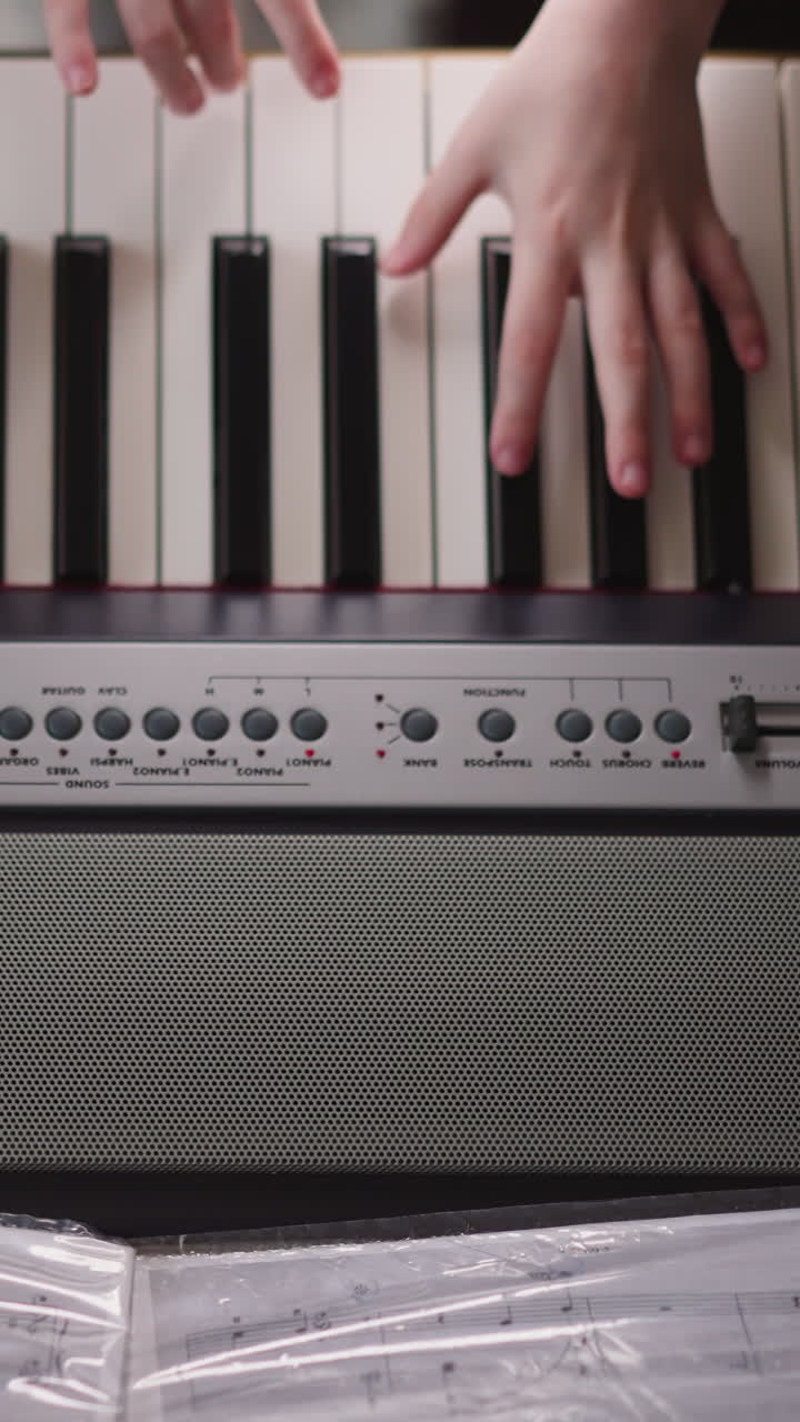 Child musician turns page of music folder and continues performance of composition. Schoolgirl plays synthesizer reading notes. Practicing in musical playing upper view