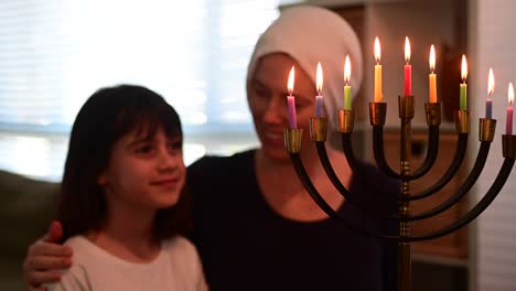 jüdische mutter und tochter schauen auf eine schöne menora am jüdischen feiertag hanukkah