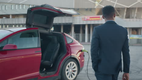 businessman leaving an electric car at charging station