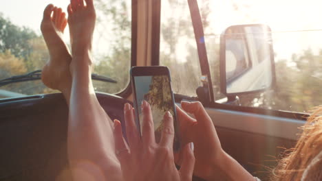 woman relaxing in a van, looking at a photo on her phone.