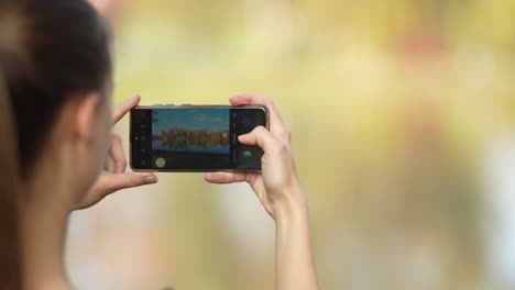 mujer joven tomando una foto de un lago