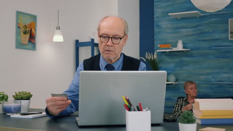 Retired man making shopping online doing payment using credit card on laptop