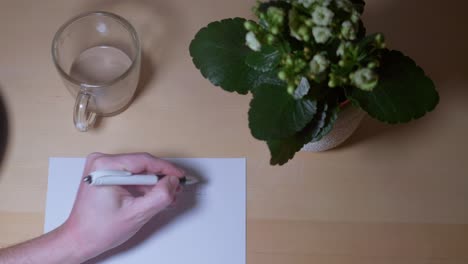 video en primer plano de una mano humana dibujando bocetos en papel en una mesa de trabajo