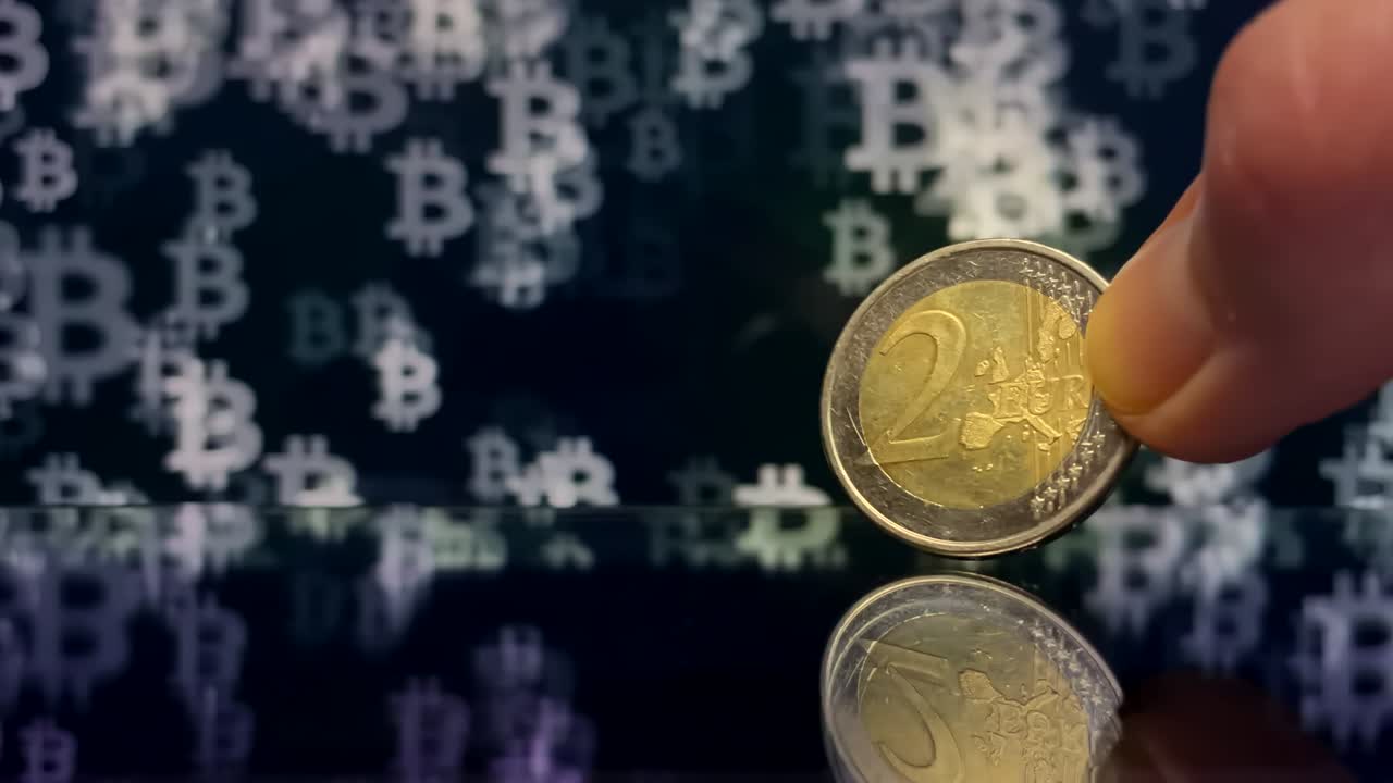 2 Euro coin in a hand on a dark background with Bitcoin symbols