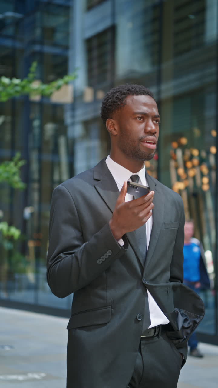 Vertical Video Shot Of Young Businessman Wearing Suit Talking On Mobile Phone Using Built In Microphone Standing Outside Offices In The Financial District Of The City Of London UK Shot In Real Time 1