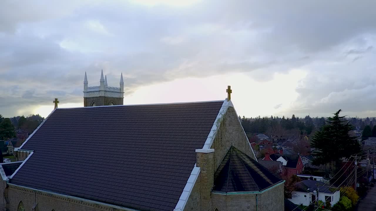 aerial side shot of church roof outlined against a dramatic sky background