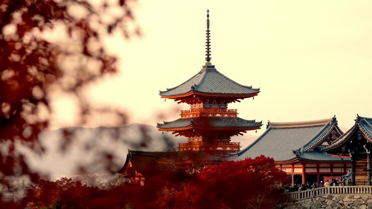 A mesmerizing view of Kiyomizu-dera Temple in Kyoto, Japan, bathed in the golden hues of sunset and surrounded by vibrant red autumn foliage.