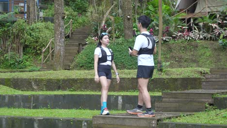 Asian couple resting and talking during outdoor workout in forest trail