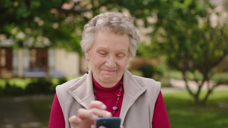 Retrato-De-Una-Anciana-Enviando-Mensajes-De-Texto-Navegando-Usando-Una-Aplicación-Para-Teléfonos-Inteligentes-Disfrutando-Del-Sol-Al-Aire-Libre