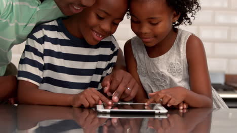 Father-using-tablet-with-his-children-in-kitchen