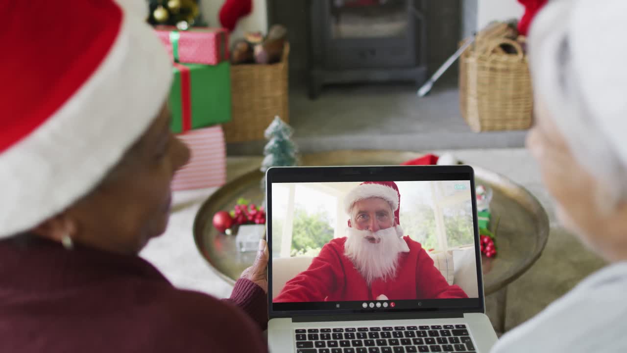 diversas amigas mayores usando una computadora portátil para una videollamada de navidad con happy santa en la pantalla