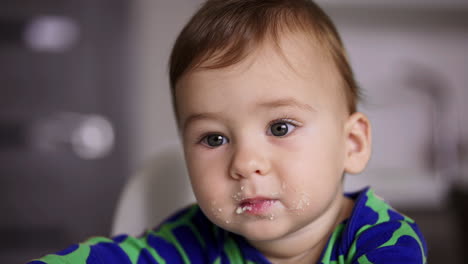 lovely cute little boy being fed from spoon. mother shoving the spoon to her son and he tries to get rid of it. close up.