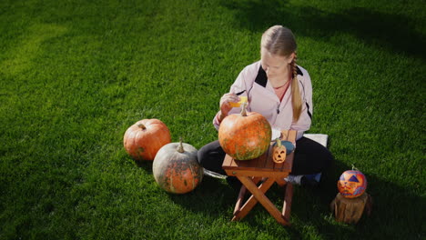 un niño decora una calabaza - prepara decoraciones festivas