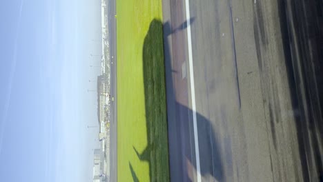 airplane-shadow-landing-in-sunny-grass-silhouette,-vertical-pov-video,-clear-blue-bright-sky