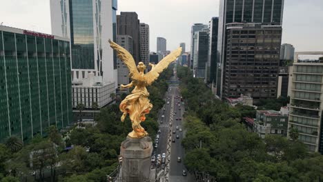 A-drone-video-offering-a-close-up-view-of-the-Angel-of-Independence,-nestled-among-the-buildings-along-Reforma-Avenue