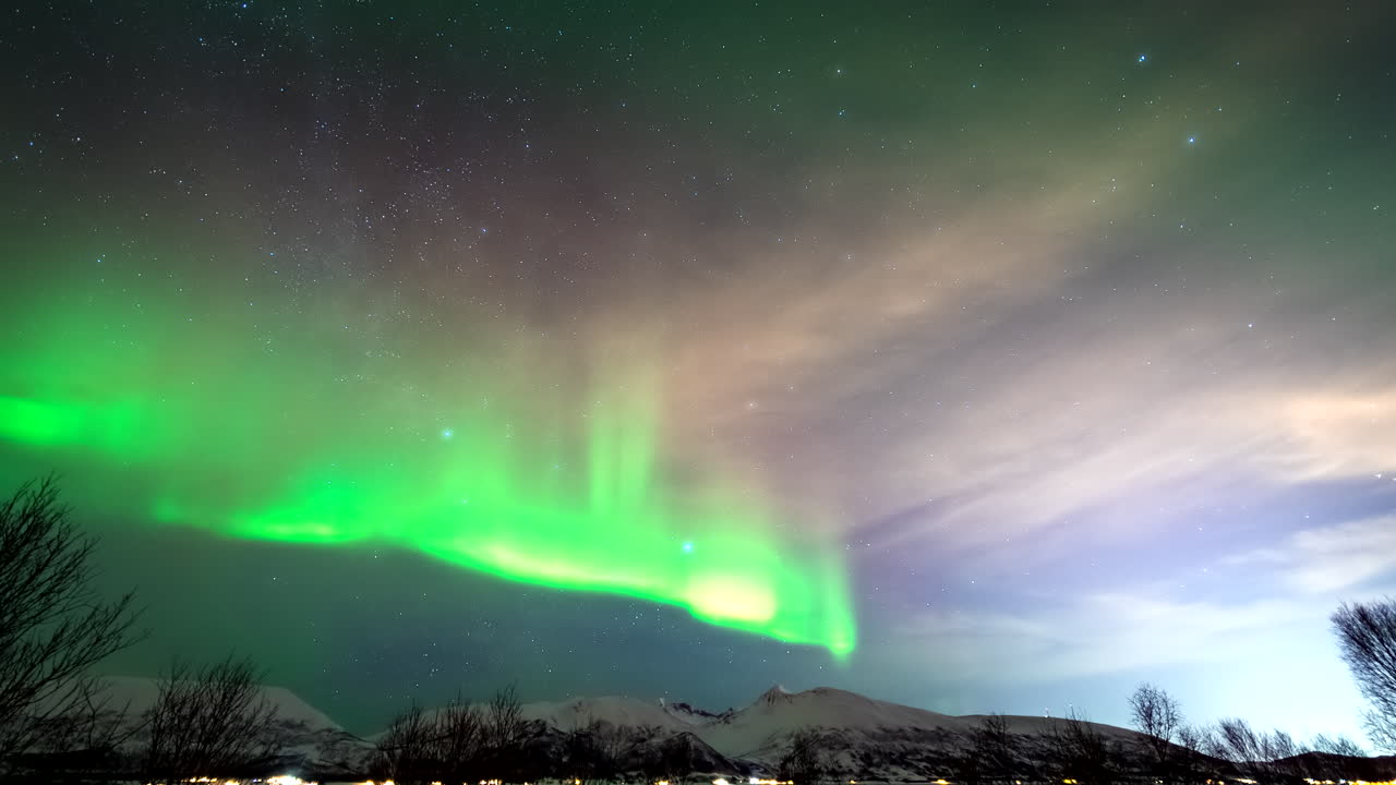 Stunning Aurora Borealis appears over Broskar fjord, serene northern lights in Norway’s arctic sky shrouded between clouds