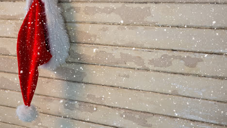 falling snow with christmas santa hat on wood