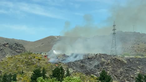 helicopter with water bucket extinguishing fire opposite cromwell heritage precinct